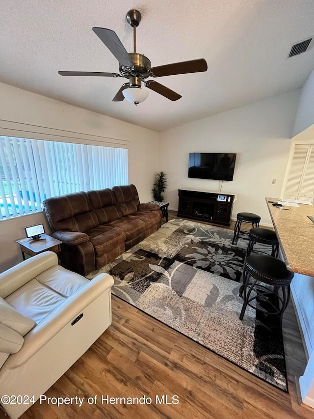 living room featuring plenty of natural light, hardwood / wood-style flooring, ceiling fan, and vaulted ceiling