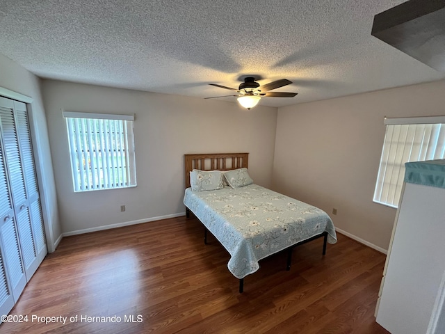 bedroom with dark wood-type flooring, a closet, a textured ceiling, and ceiling fan