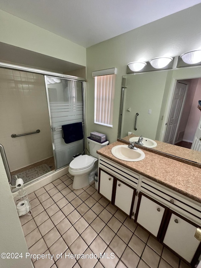 bathroom featuring tile patterned flooring, vanity, toilet, and a shower with door