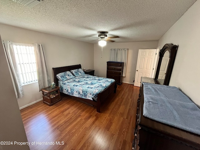 bedroom featuring ceiling fan, a textured ceiling, and dark hardwood / wood-style flooring