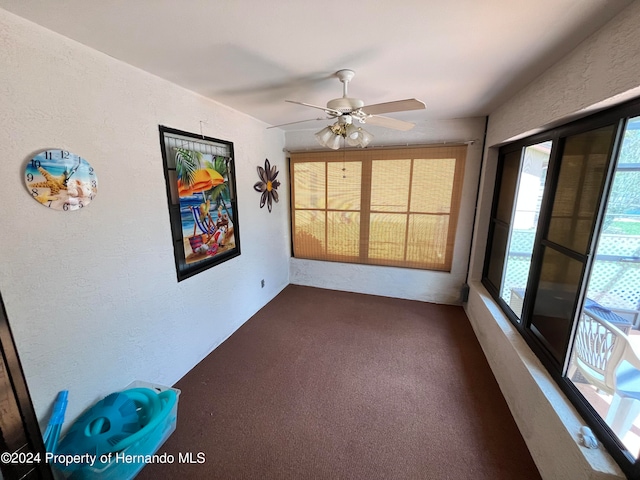 spare room with dark carpet and ceiling fan