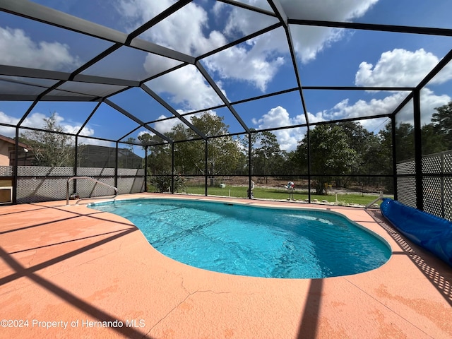 view of pool with glass enclosure and a patio area