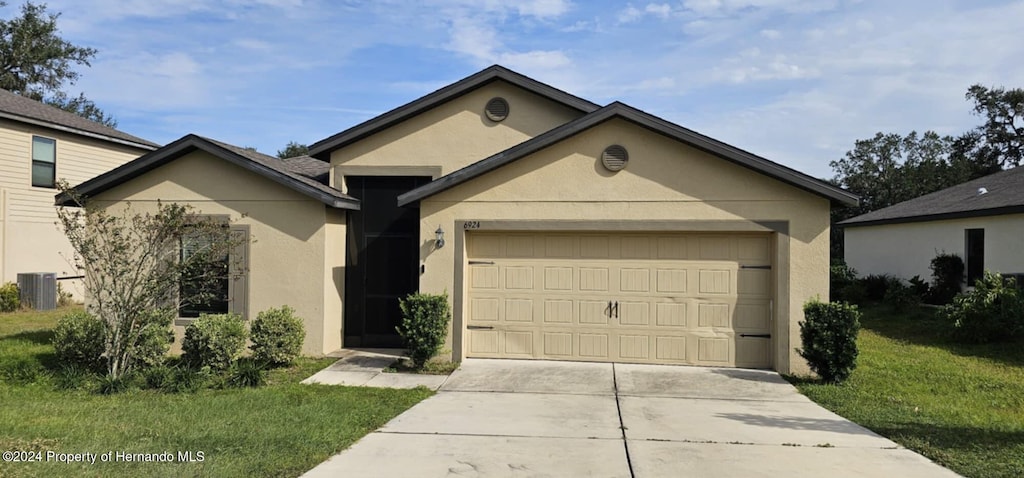 ranch-style house featuring a garage, central AC unit, and a front yard