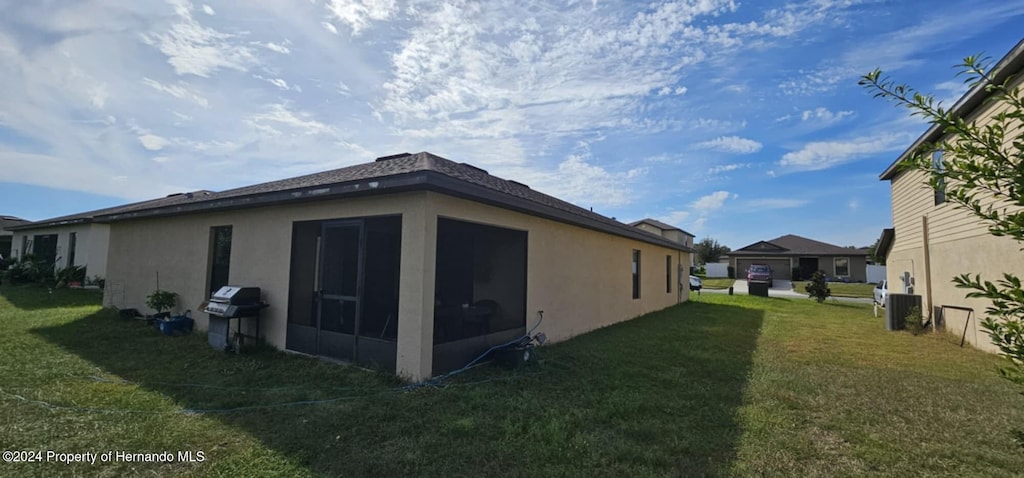 view of side of property featuring a sunroom, central AC, and a yard