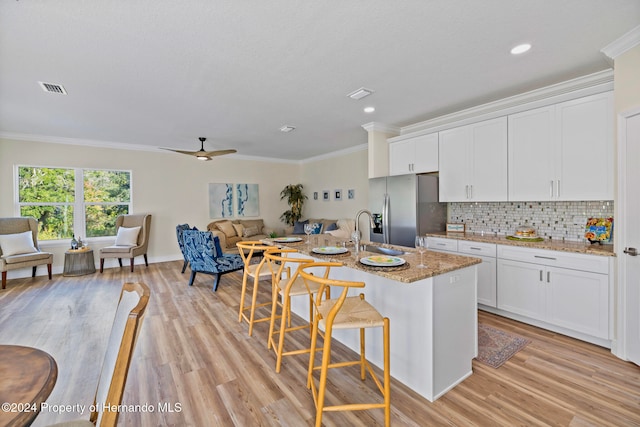 kitchen featuring light hardwood / wood-style floors, sink, a kitchen breakfast bar, light stone countertops, and white cabinetry