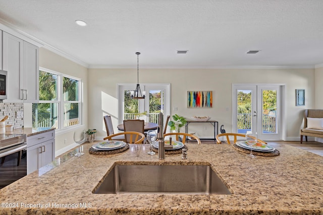 kitchen featuring sink, light stone counters, and plenty of natural light