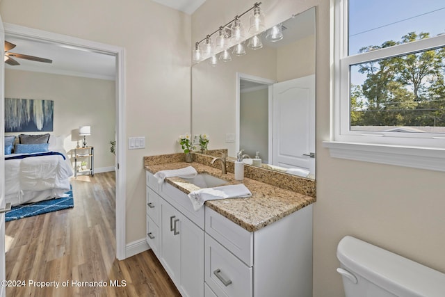 bathroom featuring crown molding, vanity, hardwood / wood-style flooring, toilet, and ceiling fan