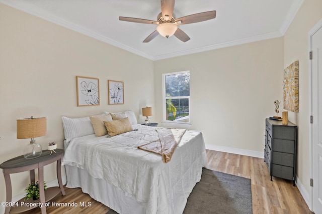 bedroom with light wood-type flooring, ceiling fan, and crown molding