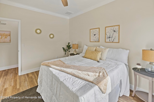 bedroom with wood-type flooring, ceiling fan, and crown molding