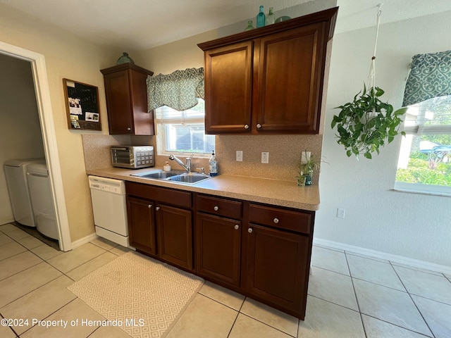 kitchen with washing machine and clothes dryer, sink, light tile patterned floors, and white dishwasher