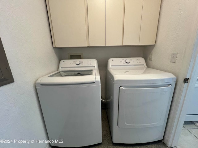 clothes washing area with cabinets, tile patterned flooring, and washer and clothes dryer