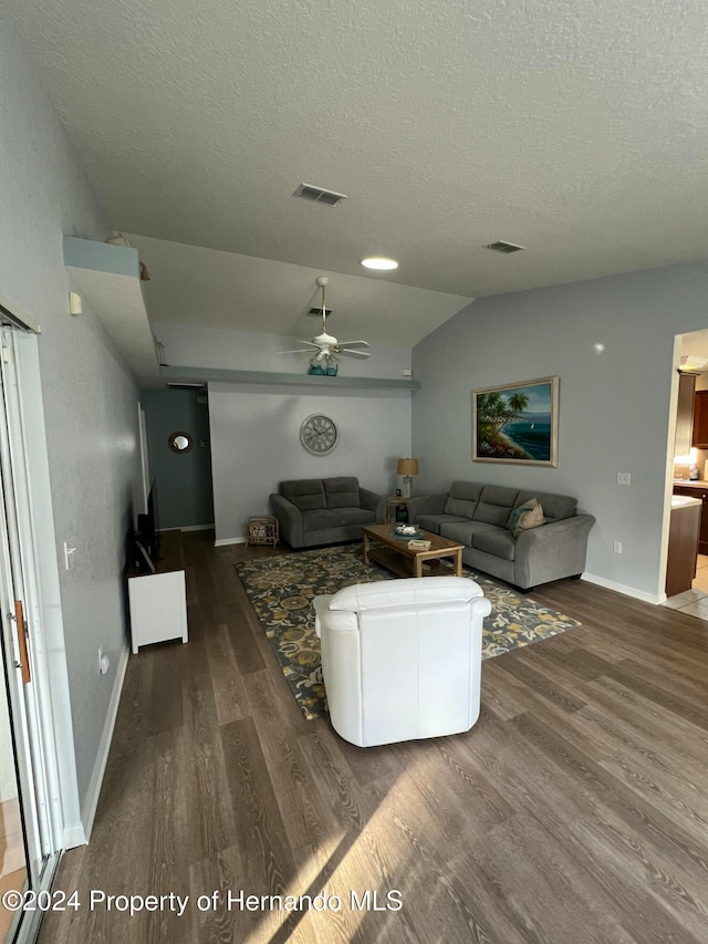 living room with dark hardwood / wood-style flooring, vaulted ceiling, ceiling fan, and a textured ceiling