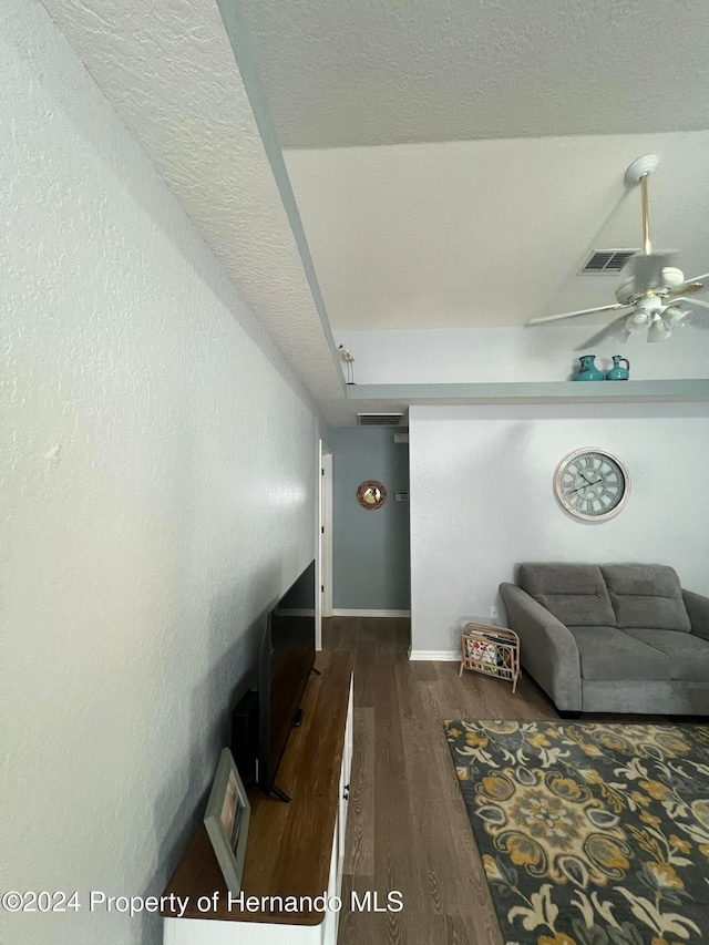 living room featuring dark wood-type flooring and ceiling fan