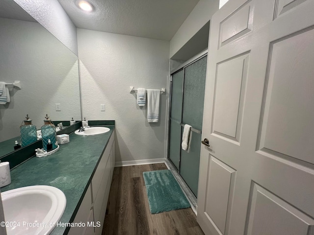 bathroom with hardwood / wood-style floors, a shower with shower door, a textured ceiling, and vanity