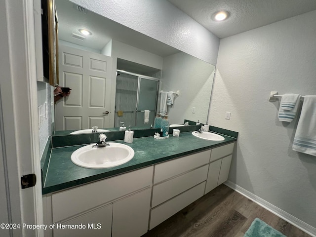 bathroom with a shower with door, wood-type flooring, a textured ceiling, and vanity