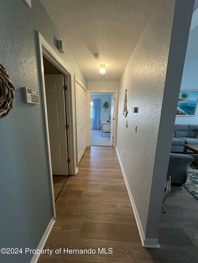 corridor with wood-type flooring and a textured ceiling