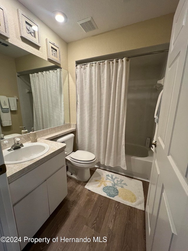 full bathroom with wood-type flooring, shower / bath combo with shower curtain, toilet, and vanity