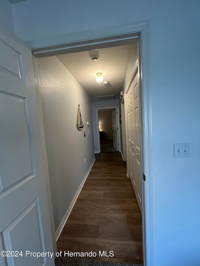 hall with dark hardwood / wood-style floors and a textured ceiling