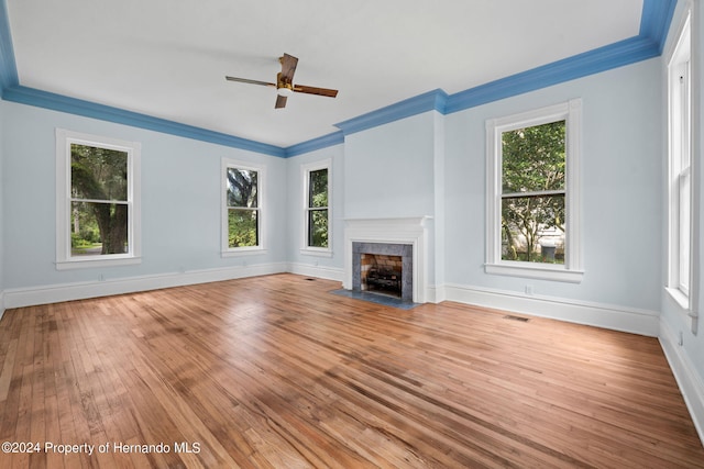 unfurnished living room with light hardwood / wood-style floors, ceiling fan, crown molding, and a tile fireplace