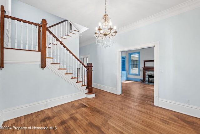 entrance foyer with hardwood / wood-style floors, an inviting chandelier, and crown molding