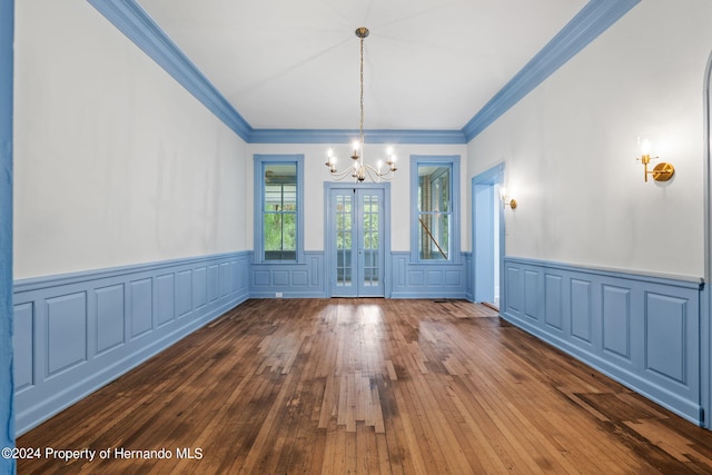 unfurnished dining area featuring hardwood / wood-style floors, a chandelier, and crown molding