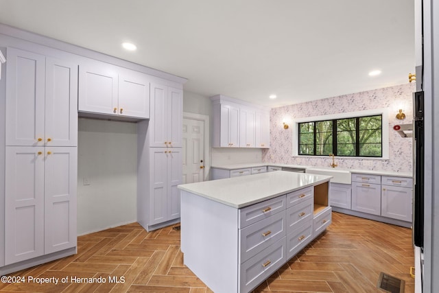 kitchen featuring light parquet floors, sink, tasteful backsplash, a kitchen island, and white cabinetry