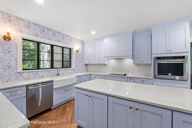 kitchen featuring stainless steel appliances, dark parquet floors, sink, and light stone counters