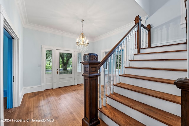 foyer featuring wood-type flooring, a notable chandelier, and ornamental molding