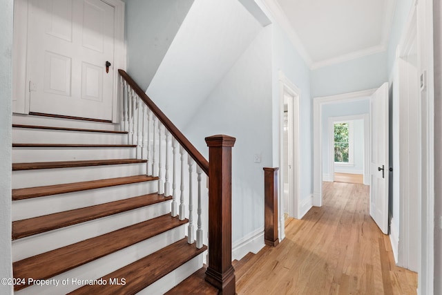 staircase with hardwood / wood-style flooring and crown molding