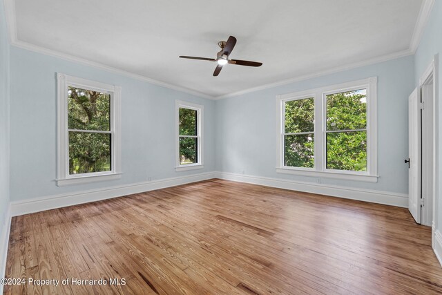 unfurnished room featuring wood-type flooring, a healthy amount of sunlight, and ornamental molding