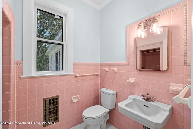 bathroom with toilet, tile walls, and sink