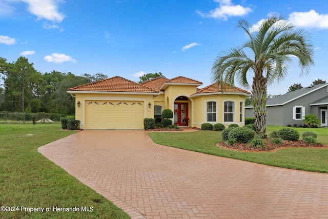 mediterranean / spanish house featuring a front lawn, a garage, and french doors