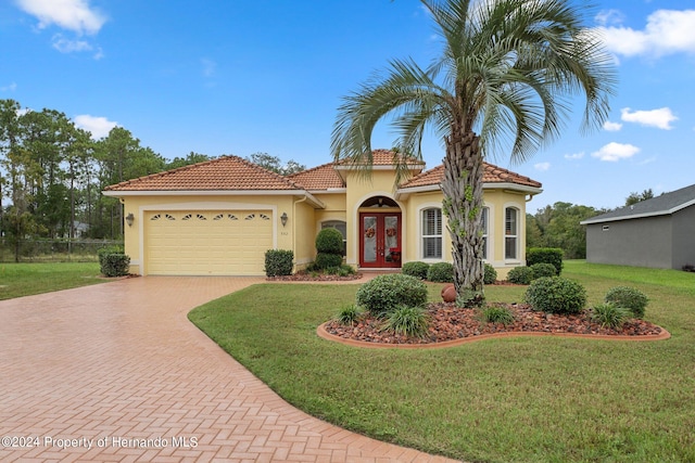 mediterranean / spanish-style home with a front yard, french doors, and a garage