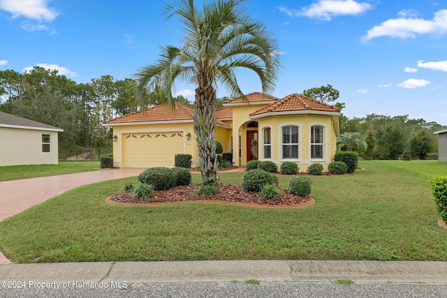 9312 Gentle Ben Ct, Weeki Wachee, FL 34613 - mediterranean / spanish home with driveway, a garage, stucco siding, a tiled roof, and a front yard