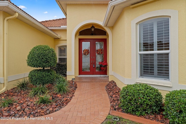 9312 Gentle Ben Ct, Weeki Wachee, FL 34613 - view of exterior entry featuring french doors and stucco siding