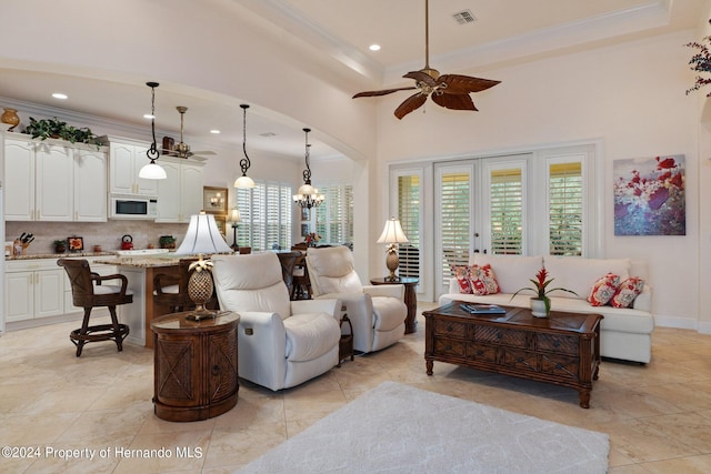 tiled living room featuring a high ceiling, ornamental molding, and ceiling fan with notable chandelier