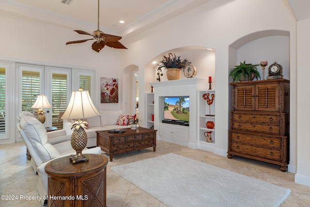 tiled living room with ornamental molding, built in features, ceiling fan, and a high ceiling