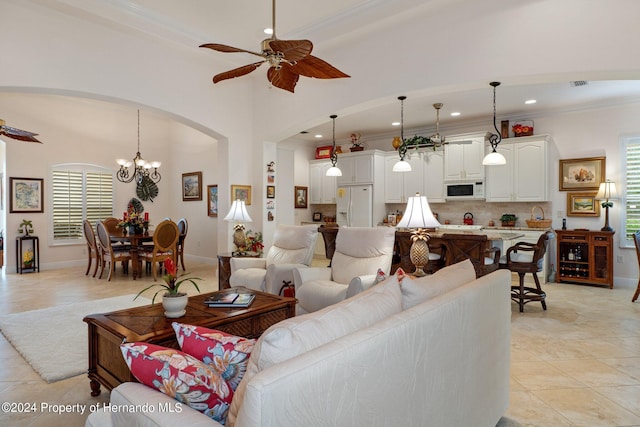 tiled living room featuring ceiling fan with notable chandelier and crown molding