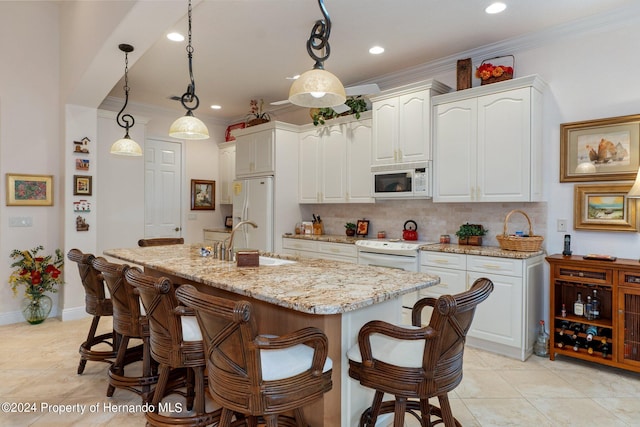 kitchen with a center island with sink, white cabinets, sink, white appliances, and decorative light fixtures