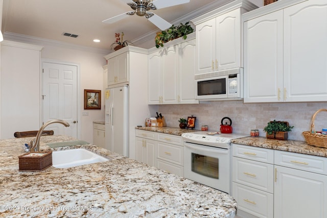 9312 Gentle Ben Ct, Weeki Wachee, FL 34613 - kitchen featuring white appliances, crown molding, white cabinets, ceiling fan, and tasteful backsplash