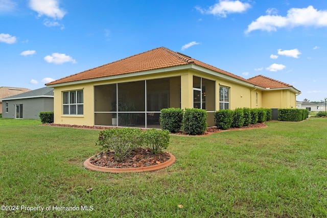 9312 Gentle Ben Ct, Weeki Wachee, FL 34613 - rear view of house featuring a tiled roof, stucco siding, a sunroom, and a lawn