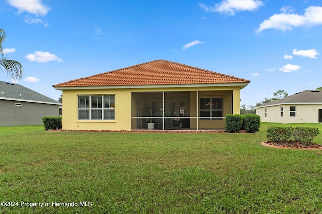 9312 Gentle Ben Ct, Weeki Wachee, FL 34613 - back of property with stucco siding, a lawn, a tile roof, and a sunroom