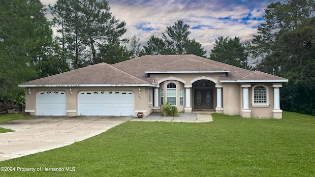 view of front of property featuring a lawn, a garage, and french doors