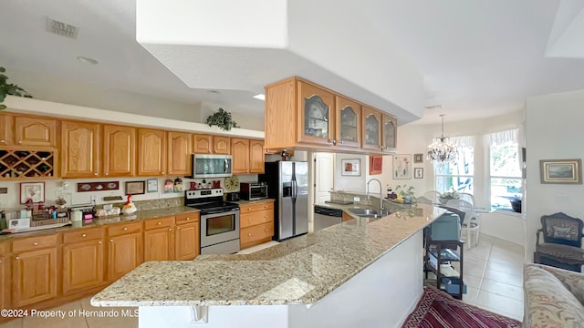 kitchen featuring an inviting chandelier, pendant lighting, a kitchen bar, light tile patterned floors, and appliances with stainless steel finishes