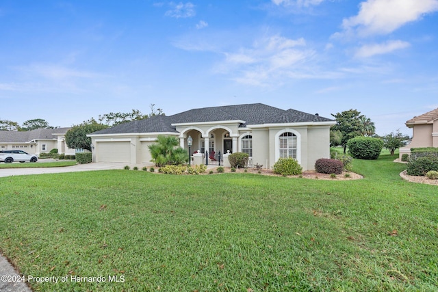 view of front of property featuring a garage, a front yard, and covered porch