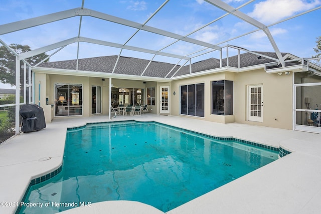 view of pool featuring a patio, glass enclosure, and grilling area