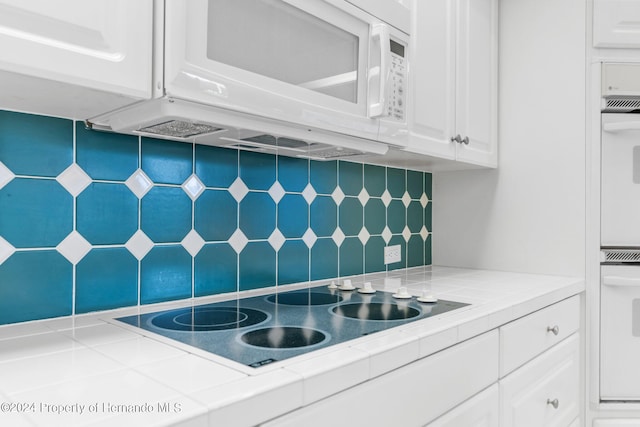 kitchen featuring white appliances, white cabinetry, tile counters, and tasteful backsplash