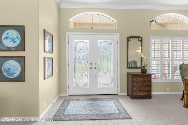 foyer entrance with ornamental molding, french doors, and light colored carpet