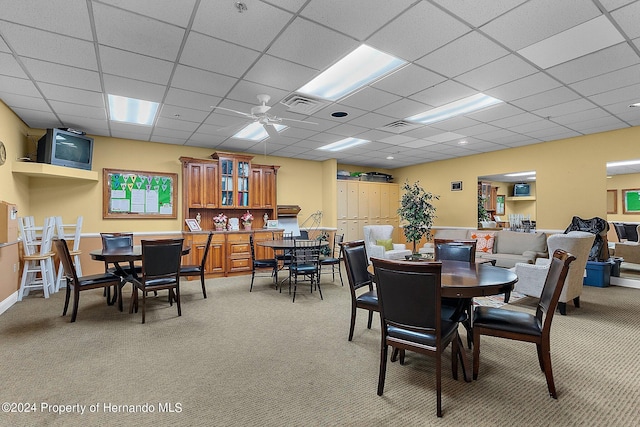 carpeted dining room with a drop ceiling and ceiling fan