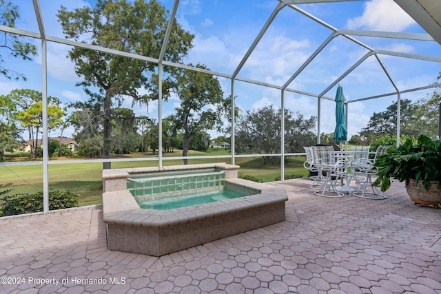 view of pool featuring a yard, a patio, glass enclosure, and an in ground hot tub